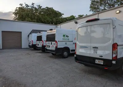 A group of white vans parked in front of a building.