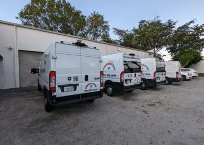 A group of white vans parked in front of a building.