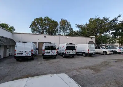 A group of white vans parked in front of a building.