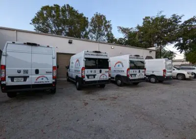 A group of white vans parked in front of a building.