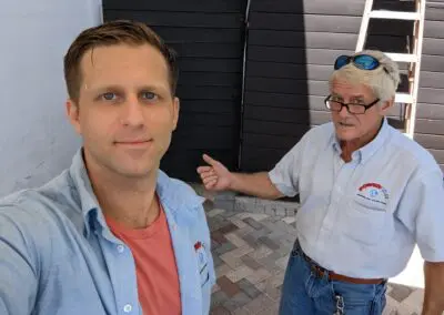 Two men standing next to each other in front of a house.