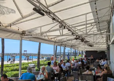 A group of people sitting at a restaurant on the beach.