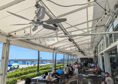 A group of people sitting at tables under a canopy.